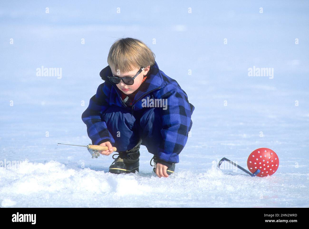 Jeune garçon (3 ans) pêche sous la glace pour la perche au réservoir Cascade, Idaho (MR) Banque D'Images