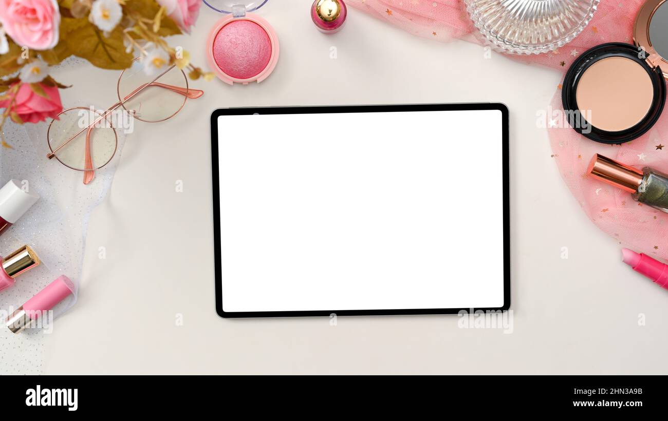 Beau design rose beauté blogger espace de travail ou bureau avec tablette numérique écran blanc maquette, lunettes, roses fleur et produits de maquillage Banque D'Images
