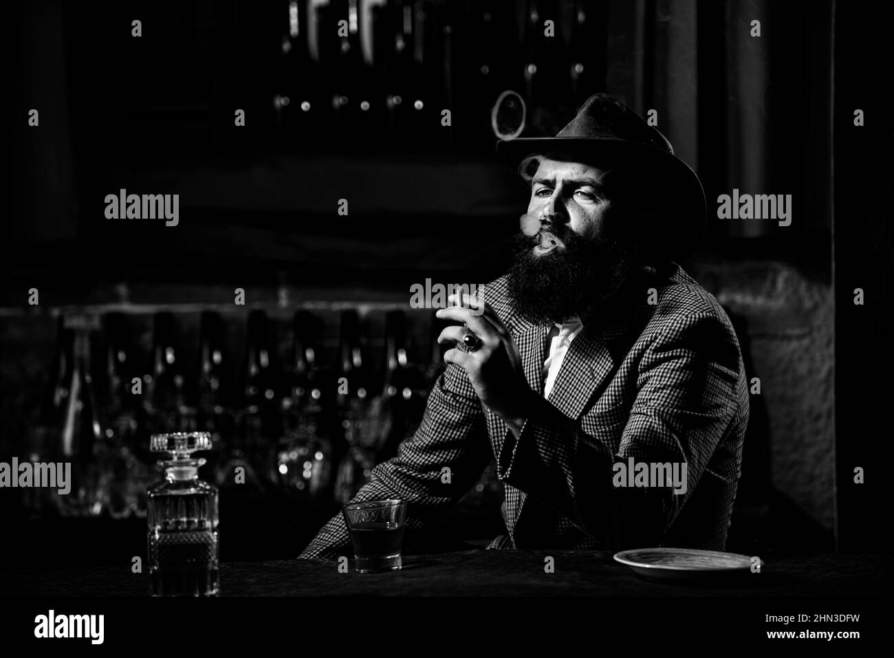 Homme attrayant fumer des cigarettes avec un verre de wiskey. Banque D'Images