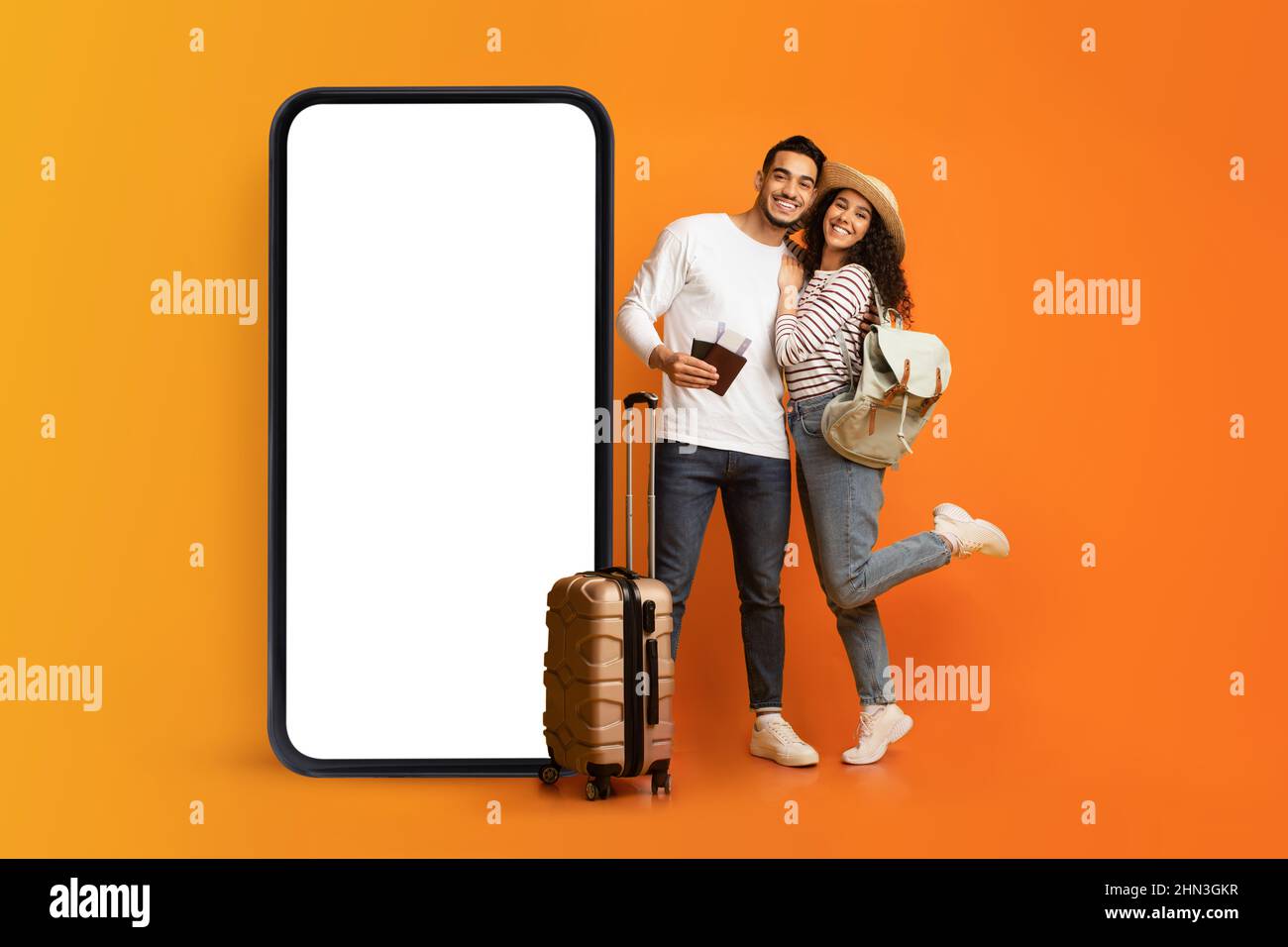 Jeune couple aimant posant près d'un immense smartphone avec écran blanc vide, offrant la publicité de l'agence de voyage, maquette Banque D'Images