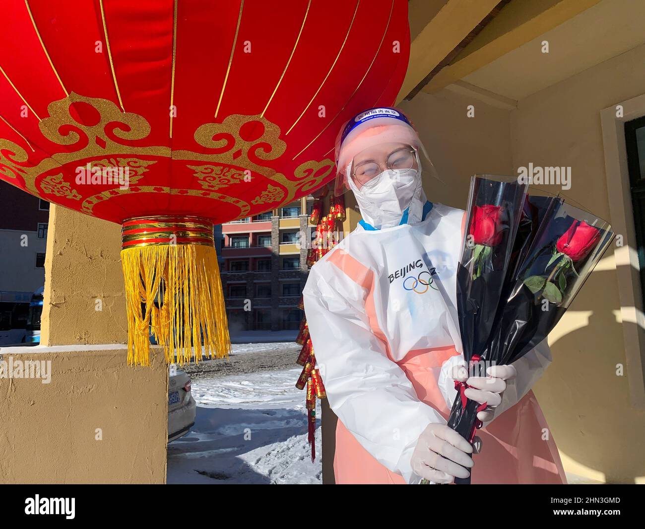 Stella, volontaire des Jeux Olympiques d'hiver de 2022 à Beijing, pose avec des roses rouges uniques alors qu'elle les remet aux journalistes et au personnel en quittant un hôtel en boucle fermée le jour de la Saint-Valentin, dans la station de ski de Thaliwoo à Zhangjiakou, en Chine, le 14 février 2022. REUTERS/Emily Roe Banque D'Images