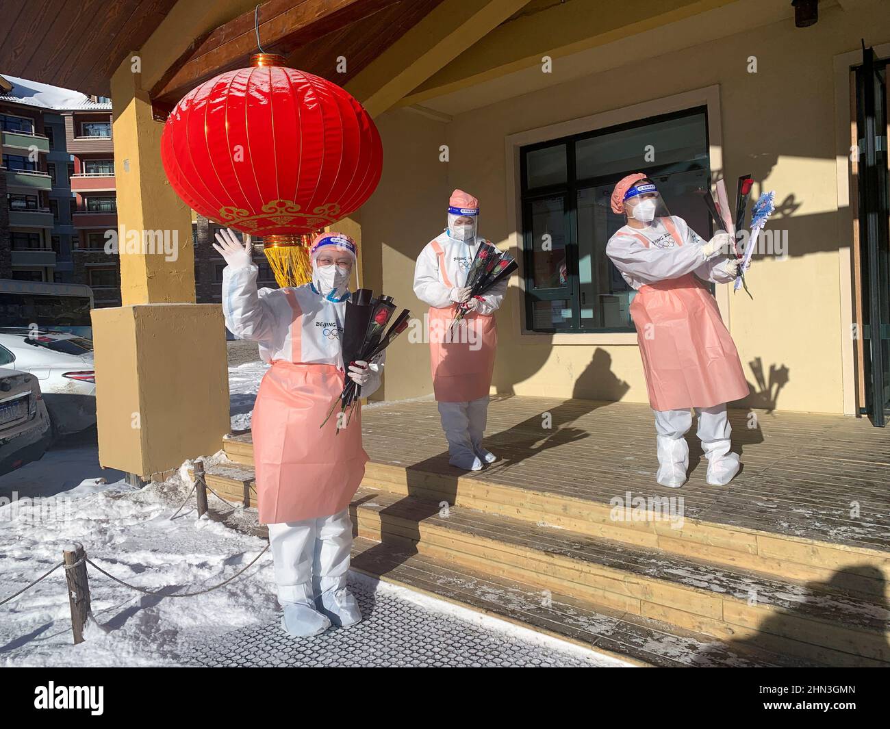 Les volontaires des Jeux Olympiques d'hiver de 2022 à Beijing posent avec des roses rouges uniques alors qu'ils les rendent aux journalistes et au personnel qui quittent un hôtel en boucle fermée le jour de la Saint-Valentin, dans la station de ski de Thaliwoo à Zhangjiakou, en Chine, le 14 février 2022. REUTERS/Emily Roe Banque D'Images