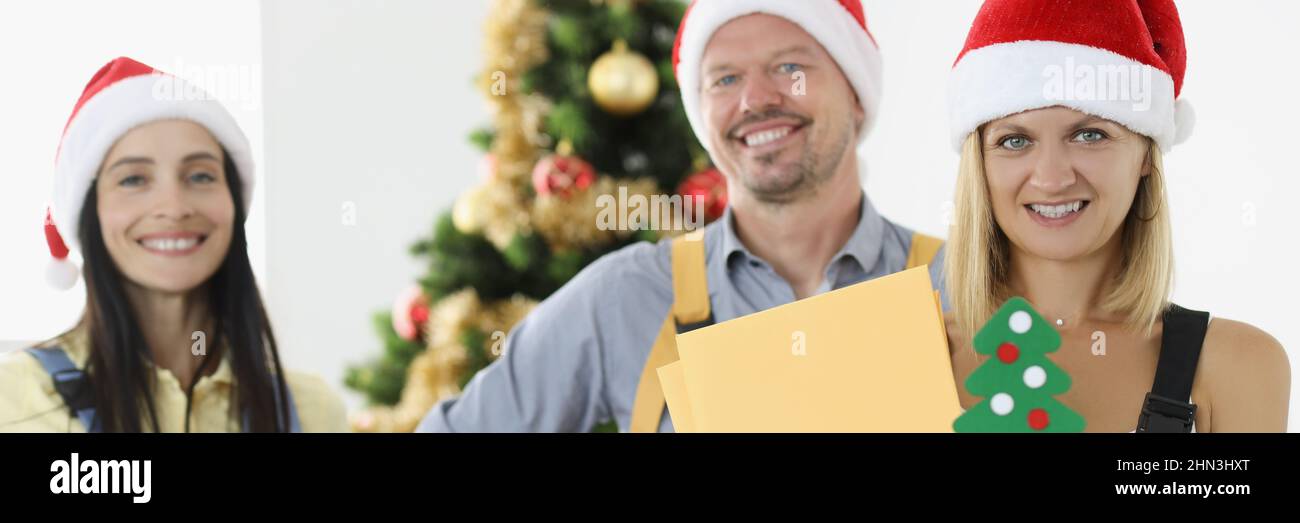 Groupe de posters en chapeaux de père noël rouges tenant des lettres et des boîtes avec des cadeaux Banque D'Images