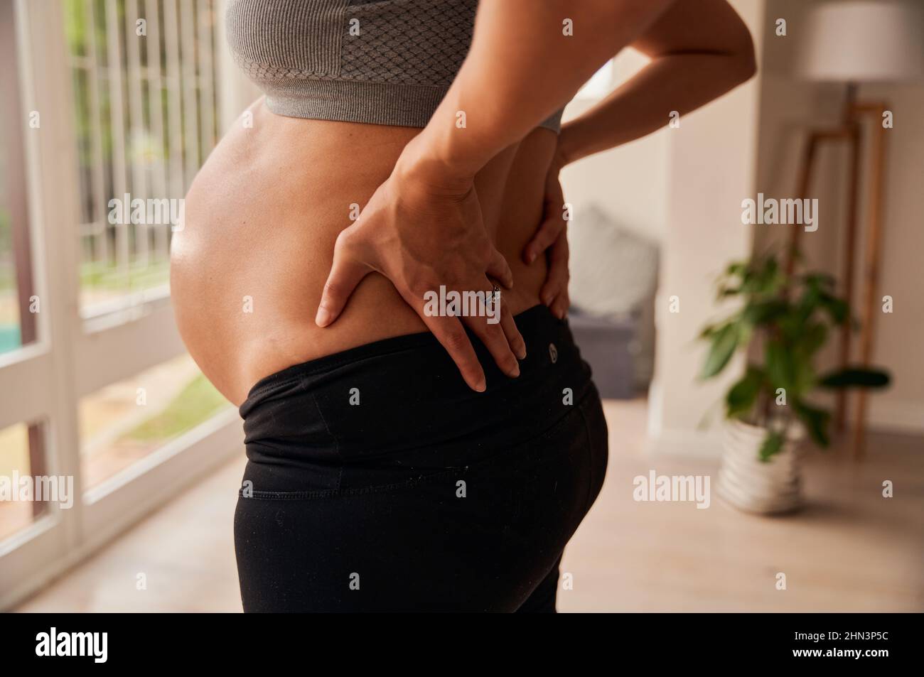 Une mère caucasienne se tient dans la salle de séjour, montrant le ventre de la femme enceinte Banque D'Images