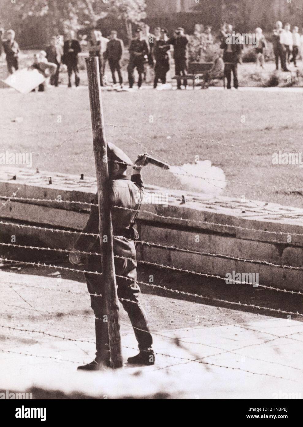 Photo d'époque de la crise de Berlin de 1961 : construire le mur. "Policiers du peuple" communiste (Volkspolizist), debout entre la clôture de la frontière et le mur, Banque D'Images