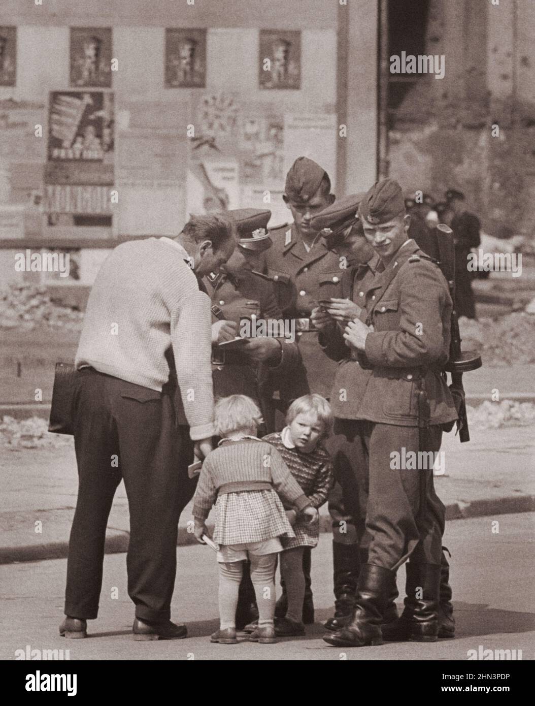 Photo d'époque de la crise de Berlin de 1961 : construire le mur. West Berliner (à gauche) accompagné de ses deux filles, cherche des informations sur sa femme fro Banque D'Images