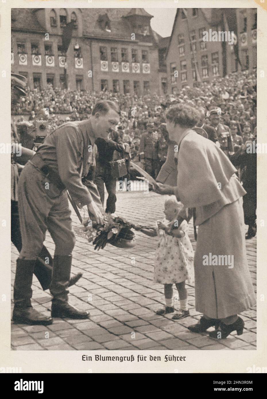 Carte postale de propagande allemande vintage : une petite fille passe un bouquet de fleurs à Adolf Hitler. 1930s seulement pour les purppes historiques! Banque D'Images