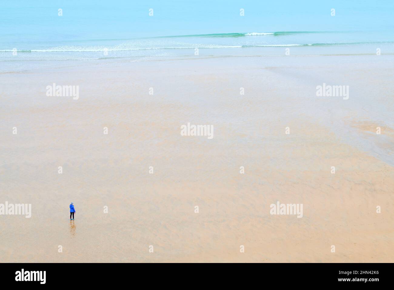 Sable fin et peu de surf sur la plage de Tolcarne à Newquay, Cornouailles, Angleterre, comme une personne solitaire se tient dans la contemplation. Banque D'Images