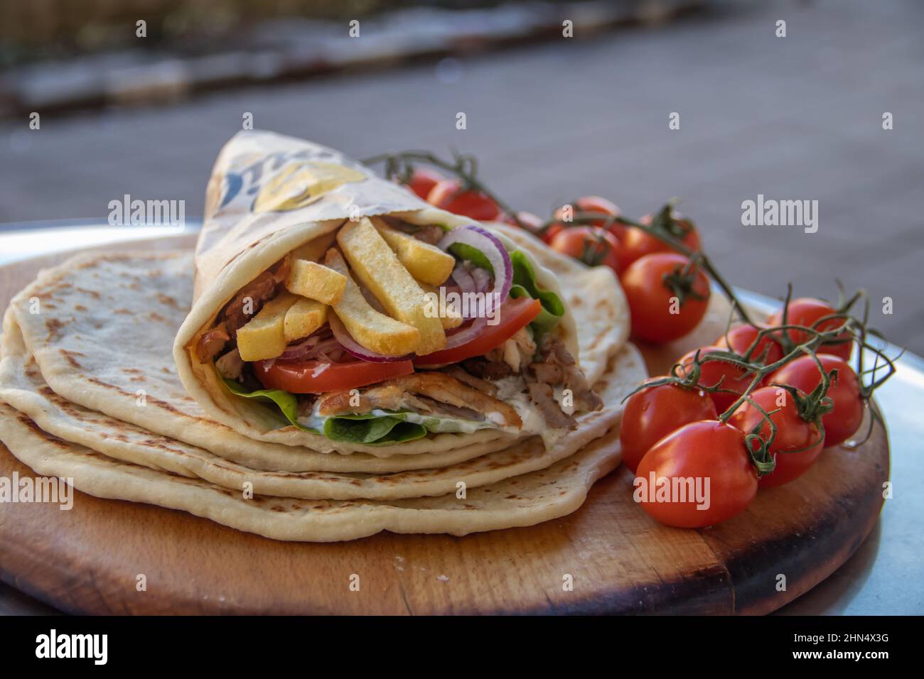 Cuisine de rue grecque Gyros à emporter, joliment enveloppée de tomates, de souvlaki, de salade grecque, d'oignons et de frites Banque D'Images