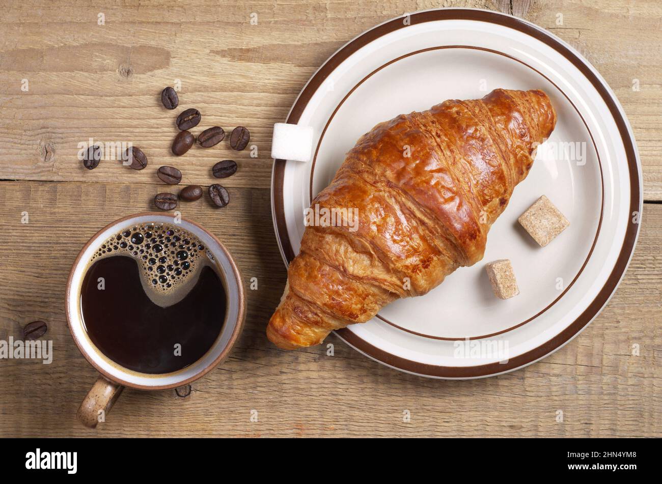 Tasse de café et croissant frais disposés sur une table en bois, vue sur le dessus. Thème du petit déjeuner ou de la pause Banque D'Images