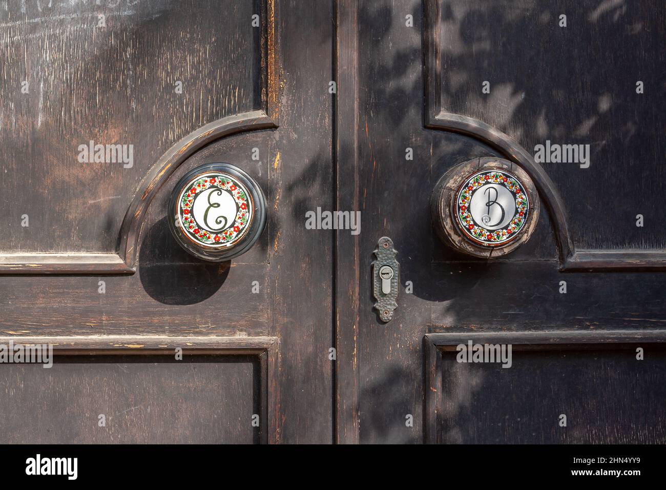 Poignées rondes avec incrustations en céramique à motifs sur porte en bois avec serrure interne. Banque D'Images