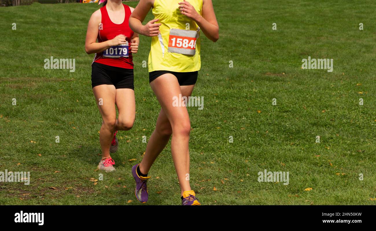 Deux jeunes filles du secondaire se présentent dans une course de 5K sur un terrain de pelouse. Banque D'Images