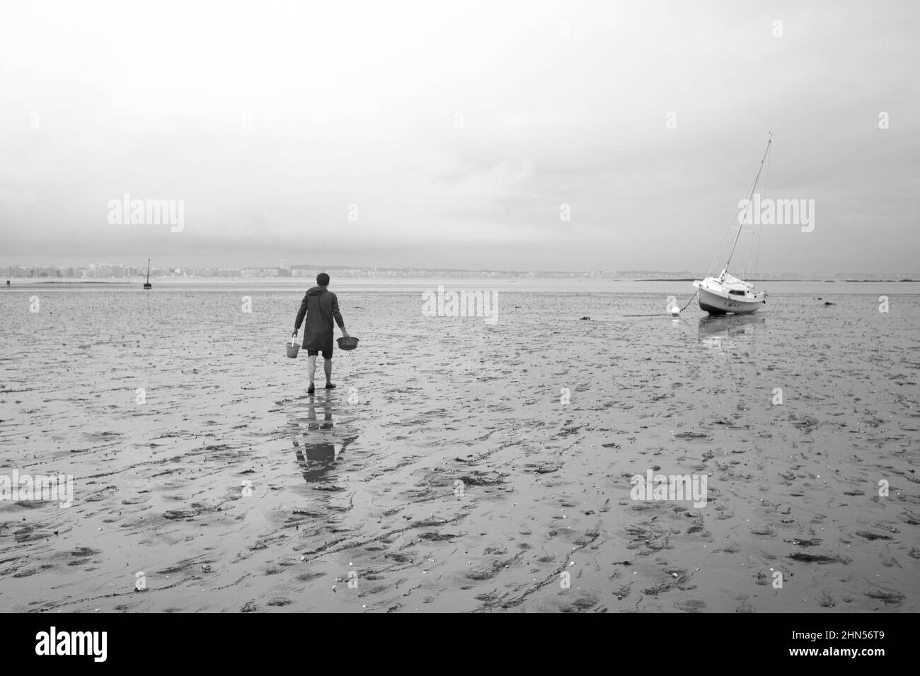 Pêcheur marchant sur une plage à marée basse Banque D'Images