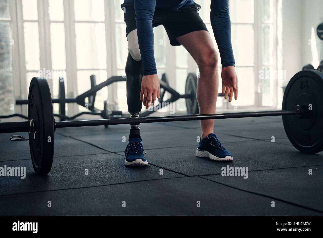 Gros plan d'un athlète paralympique masculin avec une jambe prothétique sur le point de soulever une barbell Banque D'Images