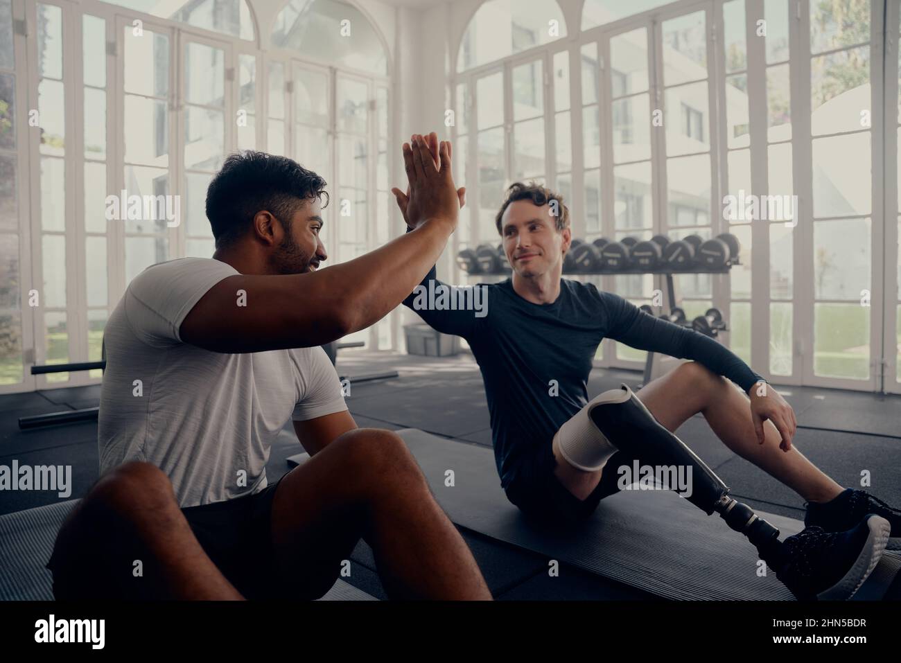 Deux amis s'entraîner dans la salle de gym - un avec une prothèse . Deux hommes de haut en train de se dépenser dans la salle de gym après une bonne séance d'entraînement Banque D'Images