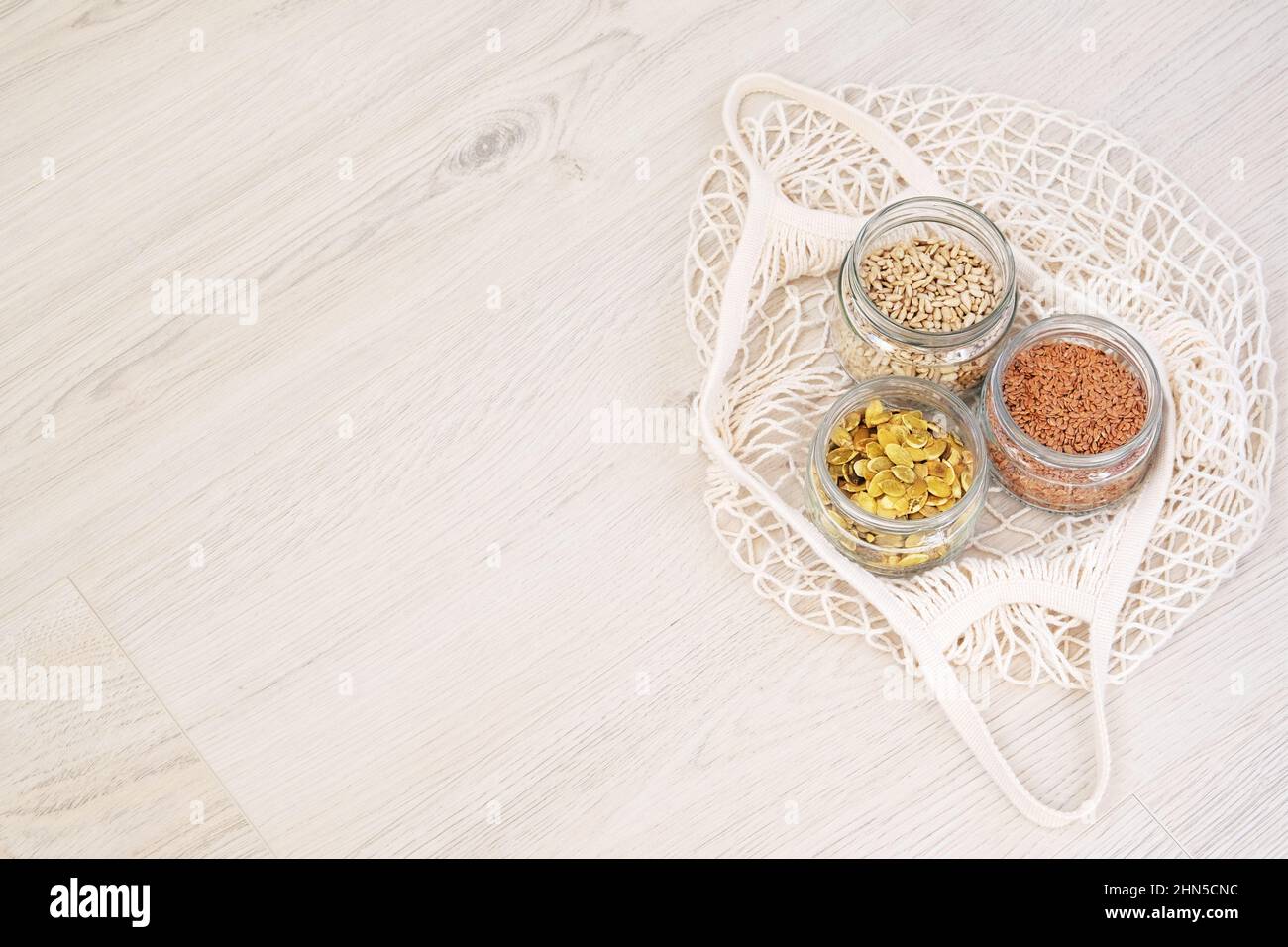 Graines biologiques dans zéro magasin de déchets. Graines de lin, tournesol et potiron en pots de verre sur fond de bois. Magasins écologiques. Copier l'espace. Banque D'Images