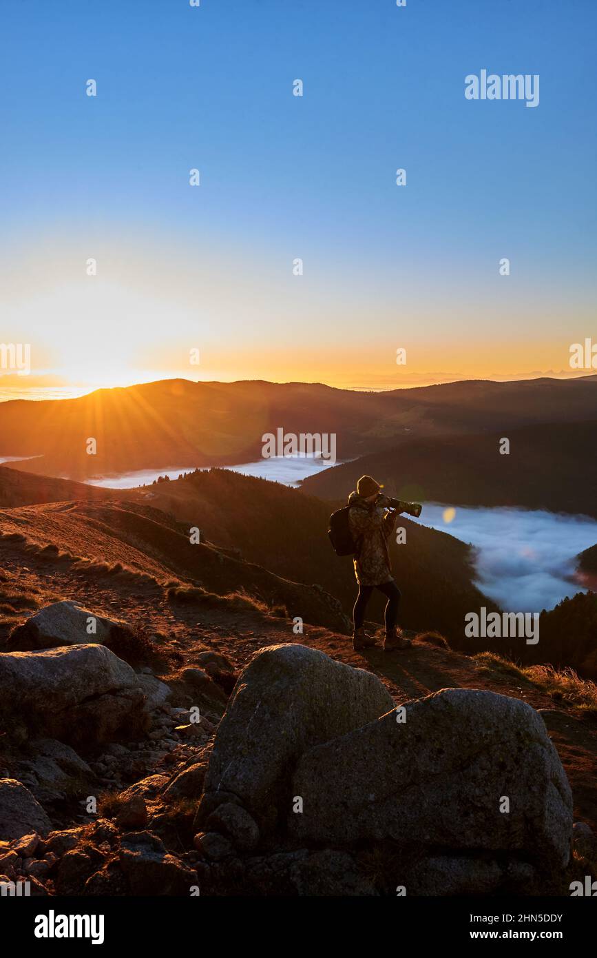 Jeune femme prenant la photographie de paysage au sommet d'une montagne avec le ciel de lever du soleil Banque D'Images