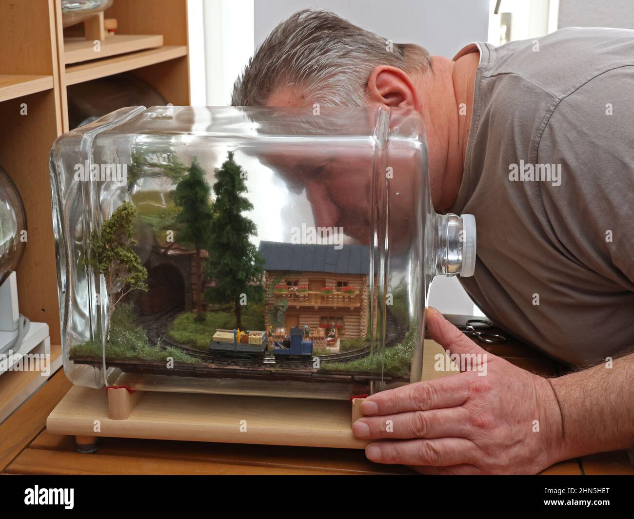 Magdebourg, Allemagne. 08th févr. 2022. Torsten Gutsche regarde un de ses paysages de chemin de fer miniature. Il construit des paysages de chemin de fer miniature en bouteilles depuis 17 ans. Le plus grand ballon a un volume d'environ 54 litres. Il passe entre huit et douze semaines à construire un chemin de fer en bouteille. Entre-temps, il en a construit 22. Credit: Peter Gercke/dpa-Zentralbild/dpa/Alay Live News Banque D'Images