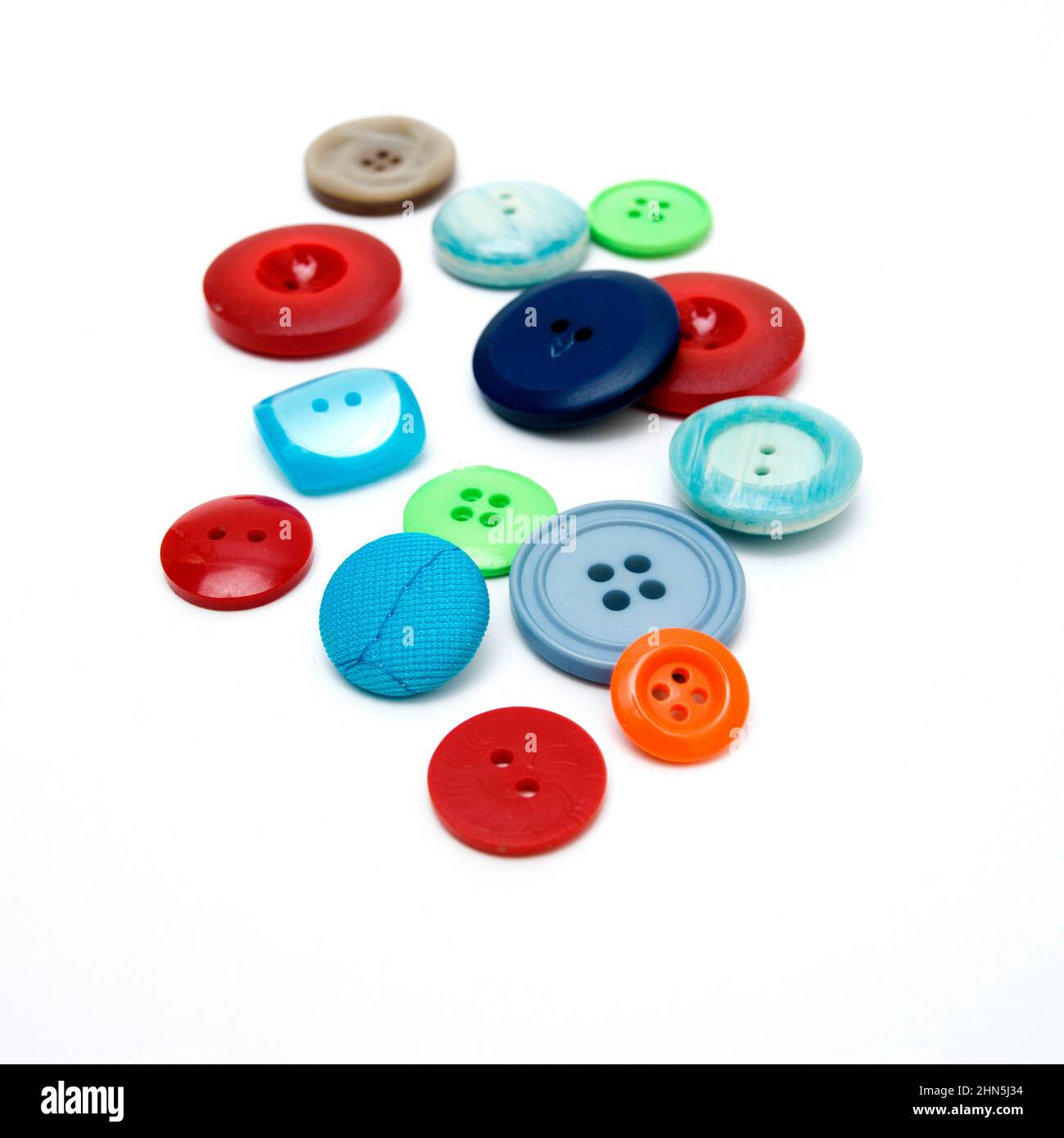 Boutons colorés assortis dispersés sur une surface blanche Banque D'Images