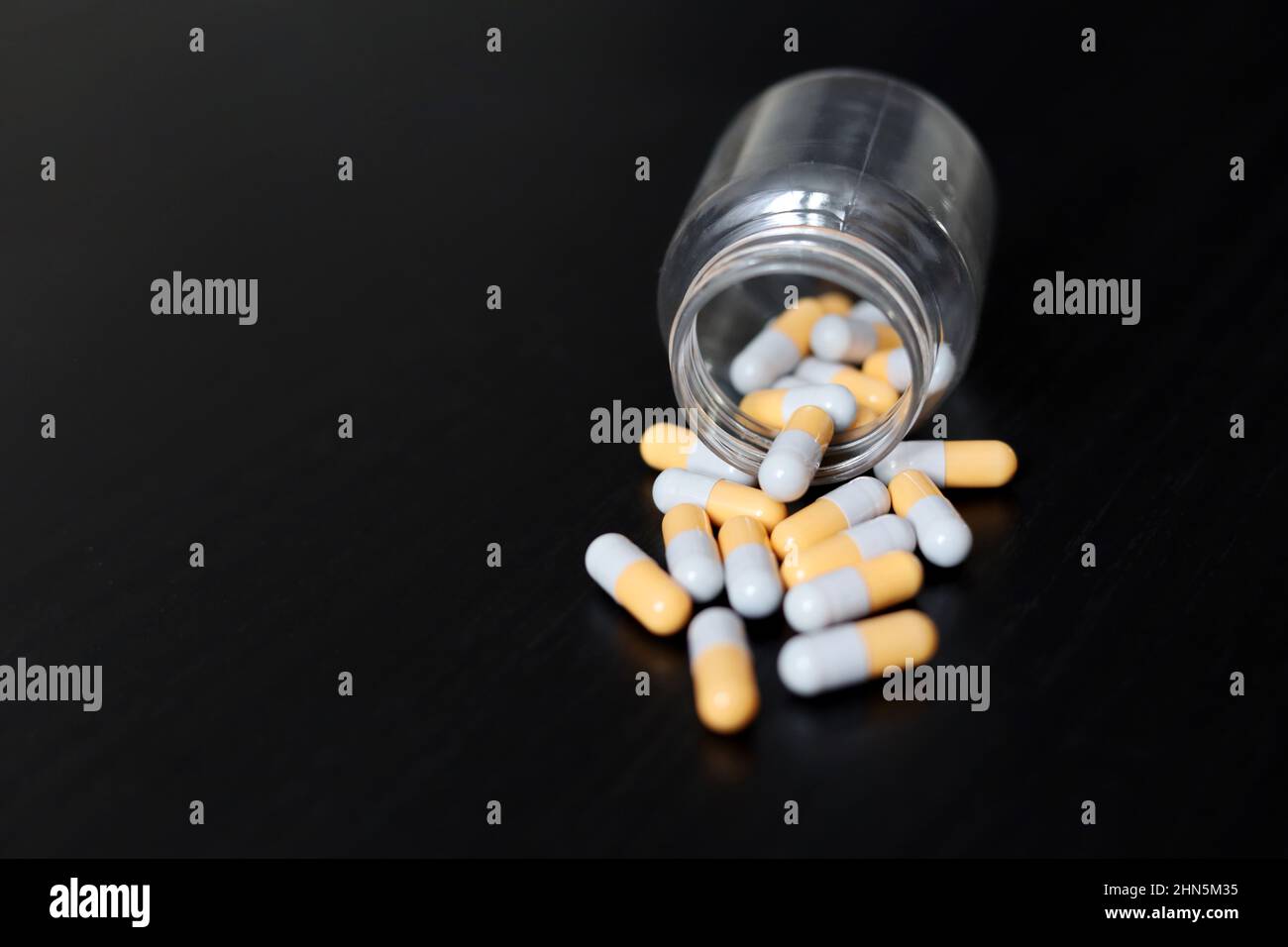 Pilules sur une table en bois sombre, médicaments en capsules dispersées d'une bouteille. Contexte pour la pharmacie, les antibiotiques, les vitamines Banque D'Images