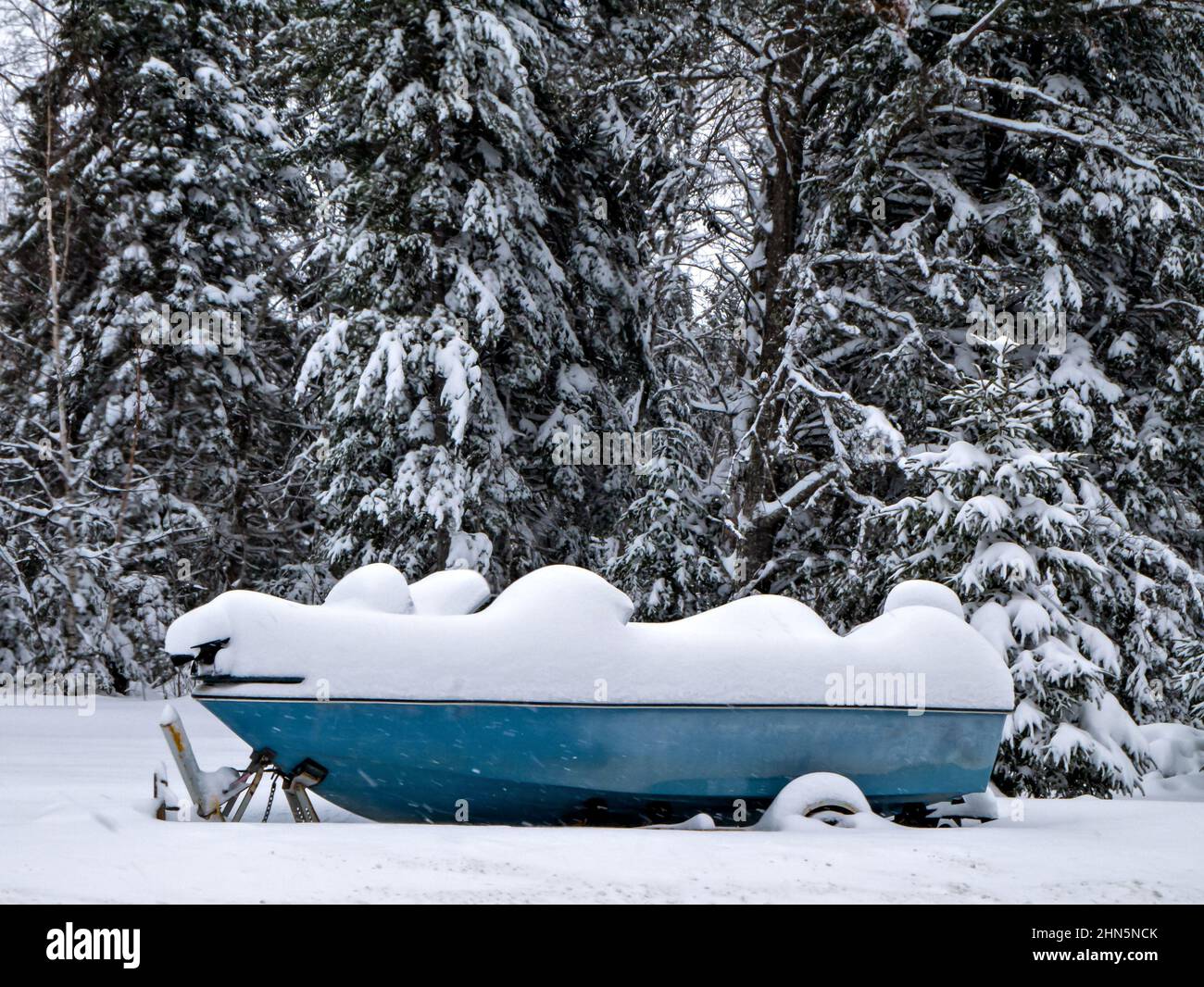Le bateau de pêche bleu sur une remorque pour l'hiver est recouvert de neige Banque D'Images