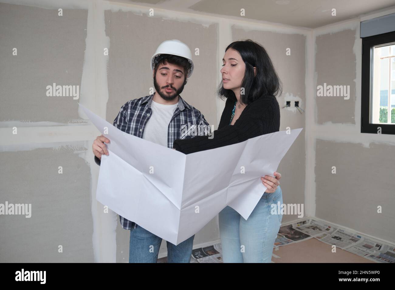 L'architecte montre l'appartement dans les plans de construction à la jeune femme intéressée. Banque D'Images