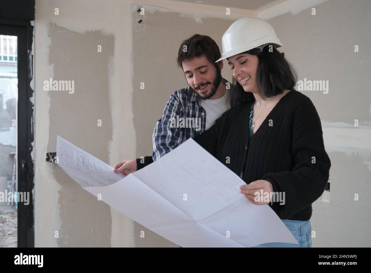 L'architecte montre l'appartement dans les plans de construction au jeune homme intéressé. Banque D'Images