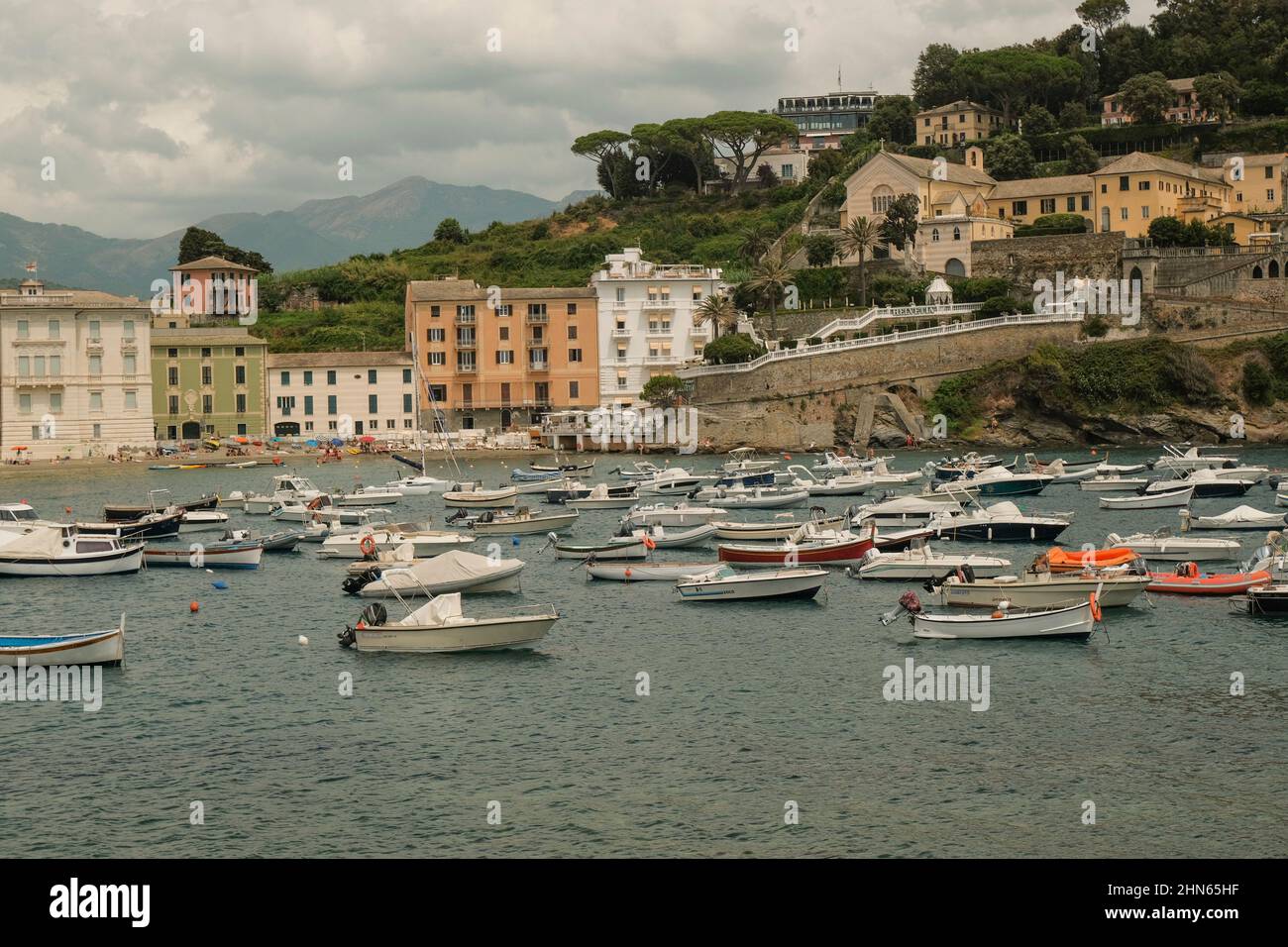Bateaux et yachts flottant dans la baie de Silence, Baia di Silenzio à Sestre-Levante, Ligurie, Italie à travers les bâtiments colorés, les montagnes, et le ciel. Banque D'Images