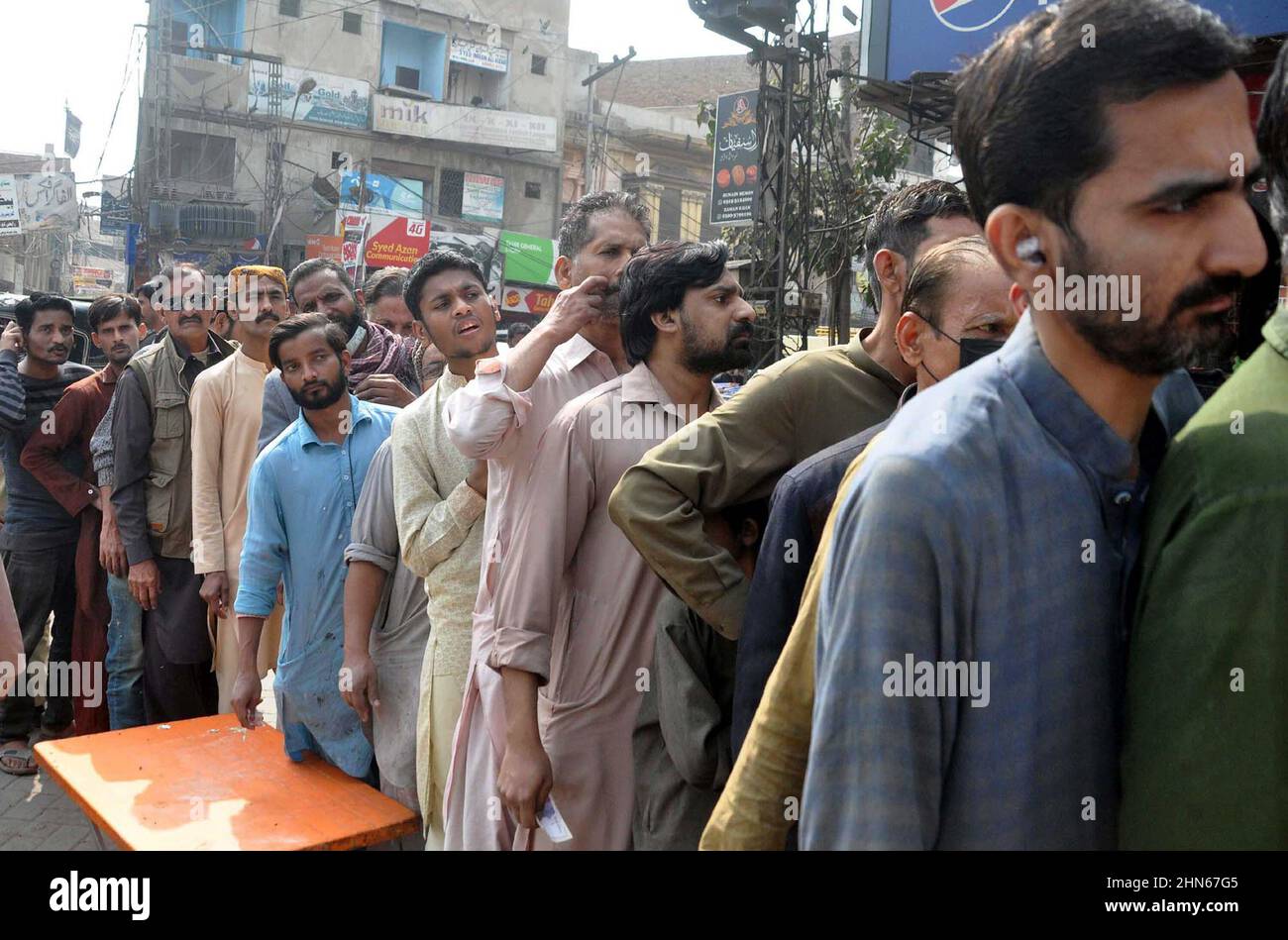 Les gens se sont rassemblés dans une file d'attente pour acheter des sacs de farine sur le prix des subventions d'un magasin de services publics mobiles vendu par le gouvernement de Sindh, comme le prix des articles généraux utilisés quotidiennement ont touché le ciel en raison de la hausse des prix dans le pays, sur une route à Hyderabad le lundi 14 février, 2022. Banque D'Images