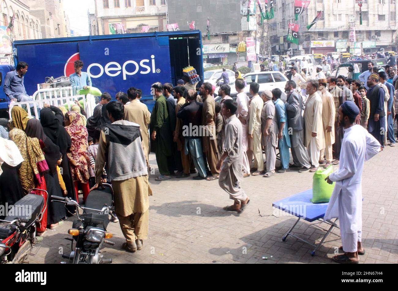 Les gens se sont rassemblés dans une file d'attente pour acheter des sacs de farine sur le prix des subventions d'un magasin de services publics mobiles vendu par le gouvernement de Sindh, comme le prix des articles généraux utilisés quotidiennement ont touché le ciel en raison de la hausse des prix dans le pays, sur une route à Hyderabad le lundi 14 février, 2022. Banque D'Images