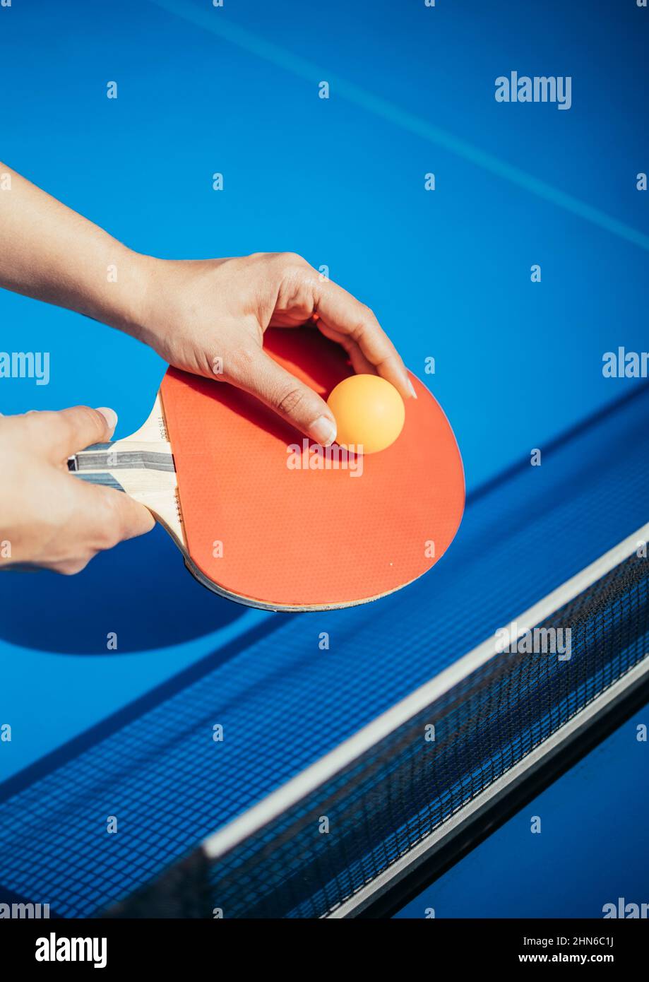 Une main de femme tenant une raquette de tennis de table à côté du filet Banque D'Images