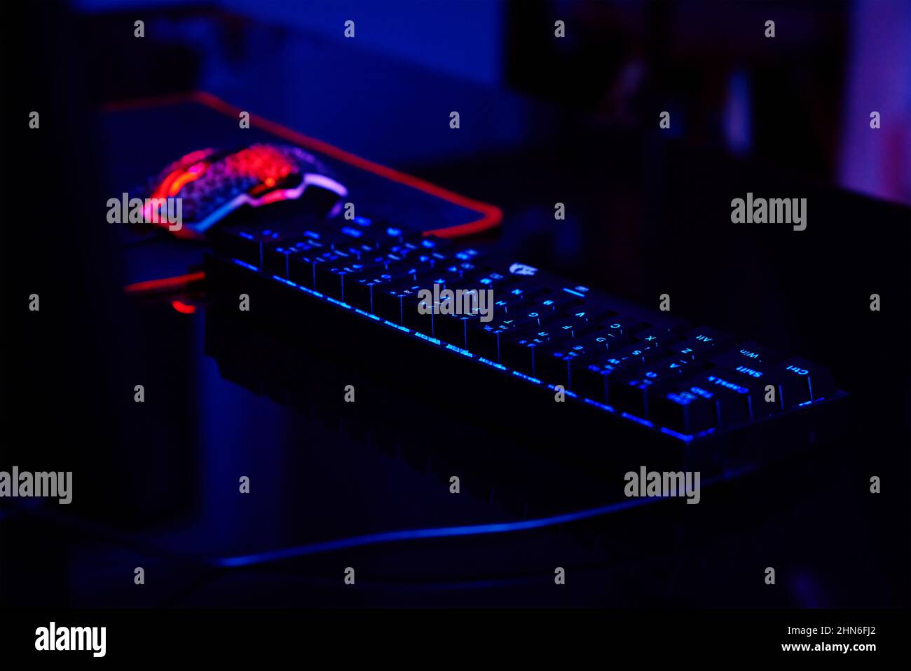 PC avec clavier rvb pour les jeux vidéo d'ordinateur avec fond de couleur néon, pièce sombre avec espace de jeu sans personne Banque D'Images