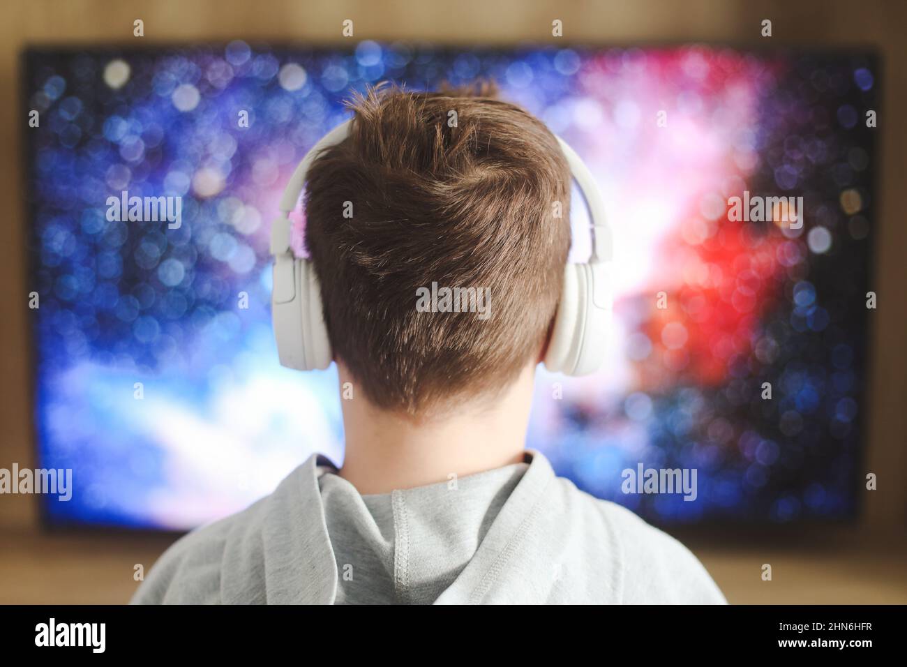 Garçon dans un casque regardant la télévision, garçon adolescent jouant à un jeu vidéo devant l'écran à la maison. Banque D'Images