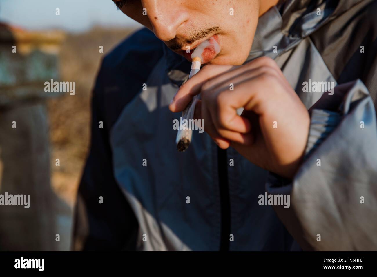 Gros plan d'un jeune homme qui fume un joint de marijuana à l'extérieur Banque D'Images
