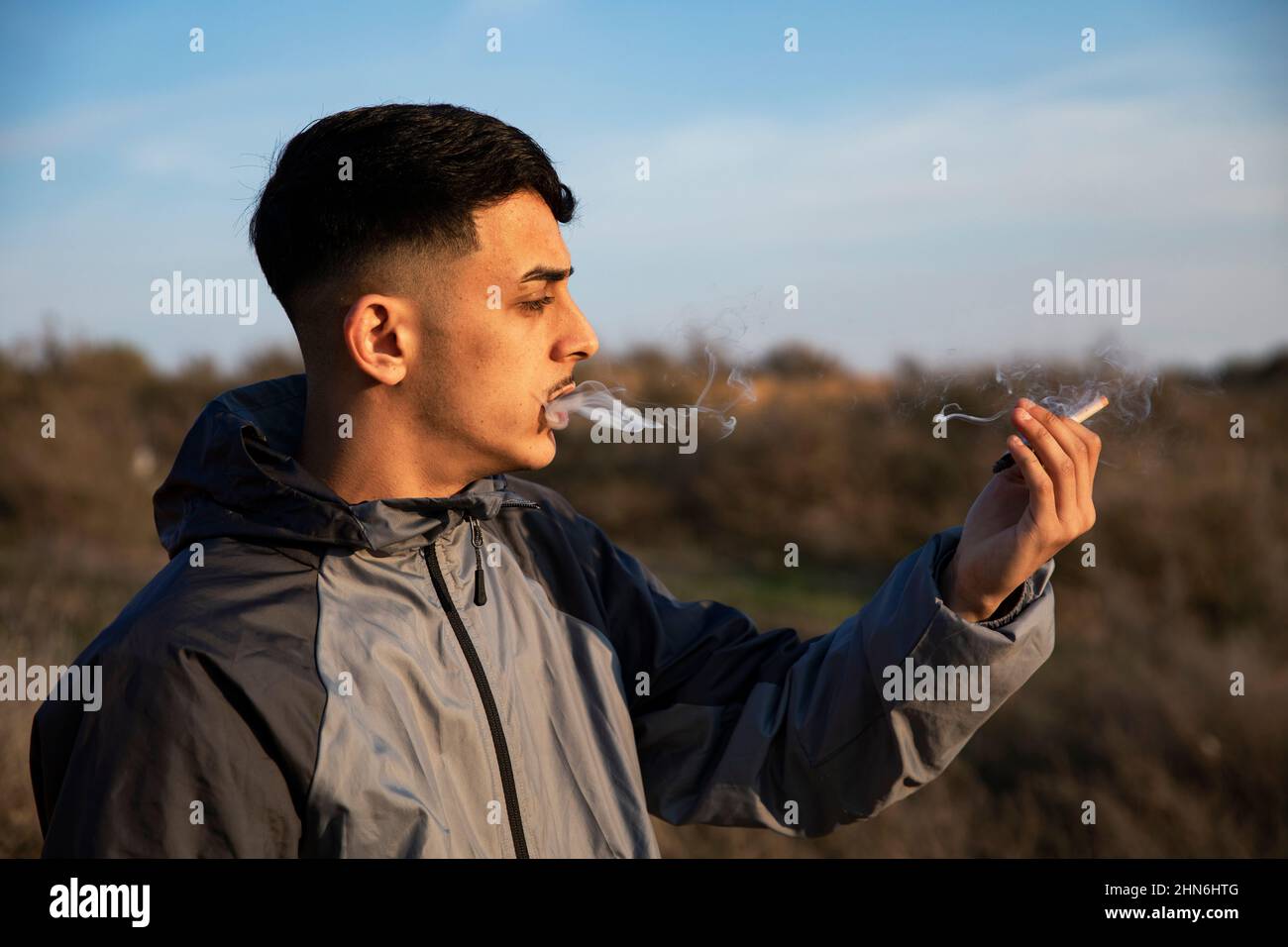 Gros plan d'un jeune homme qui fume un joint de marijuana à l'extérieur Banque D'Images