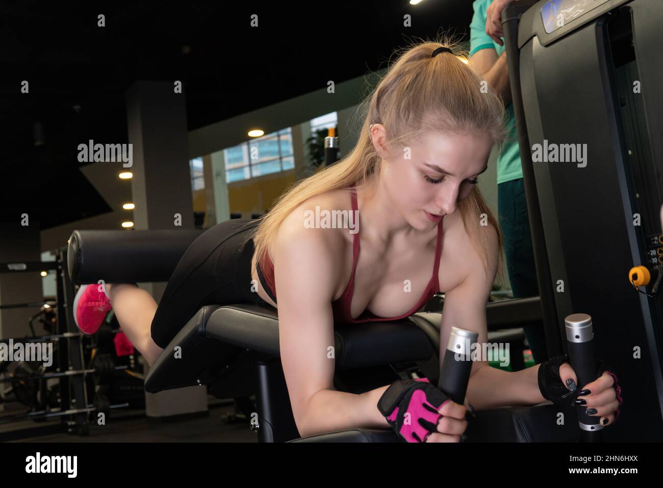 L'entraînement dirigé par un instructeur aide un beau client à effectuer des exercices dans un club de remise en forme, le concept de jouer du sport avec un loisir professionnel de gym Banque D'Images
