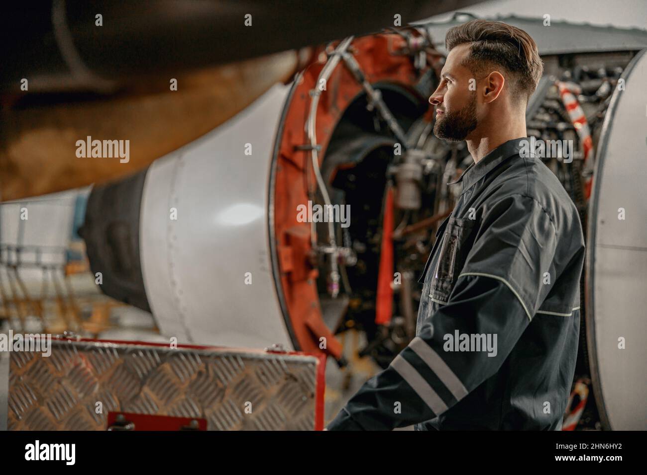 Homme barbu mécanicien d'aviation travaillant dans le hangar Banque D'Images