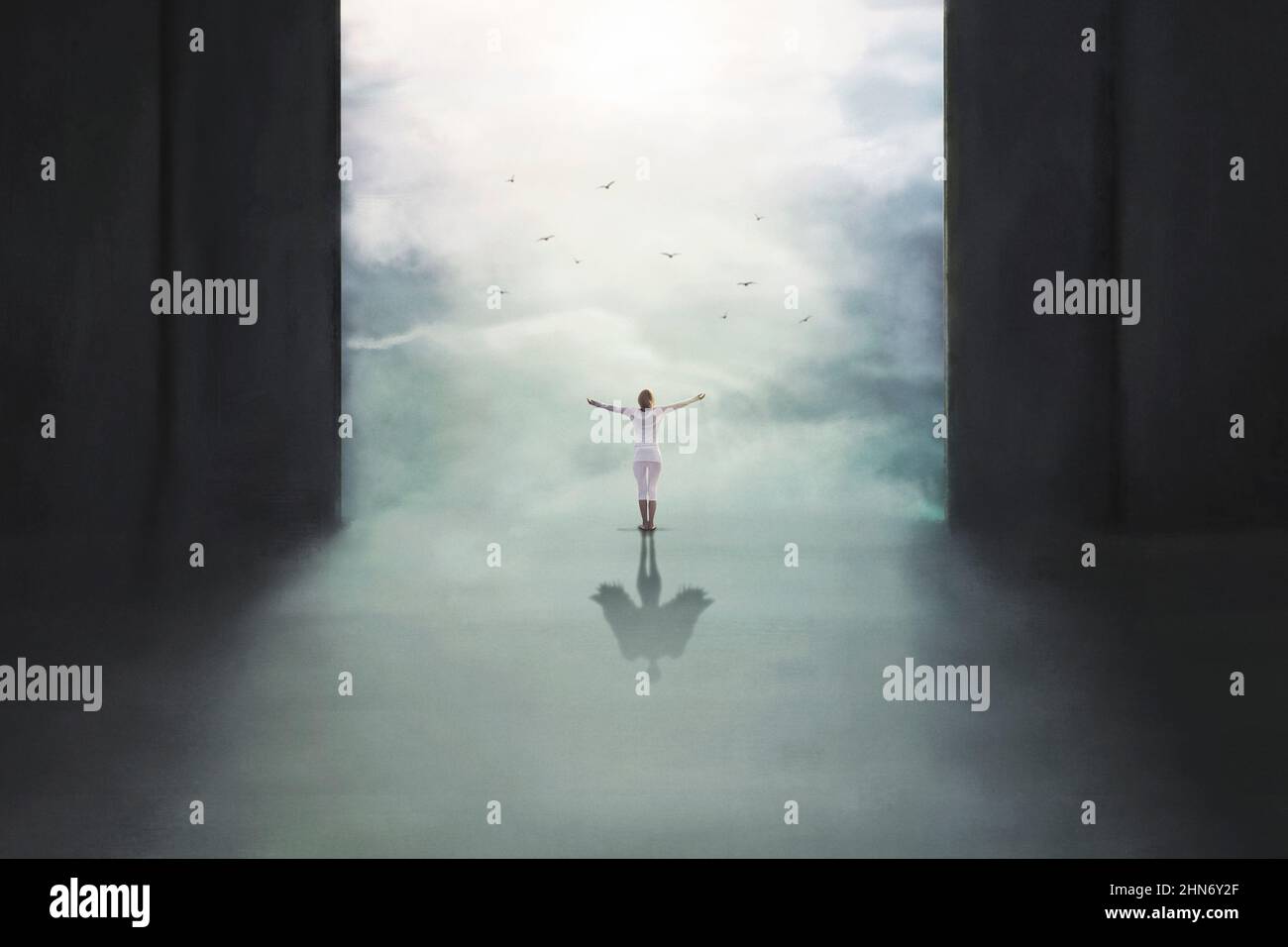 Une femme aux bras étirés jusqu'au ciel forme une ombre surréaliste sur le sol avec ses ailes Banque D'Images