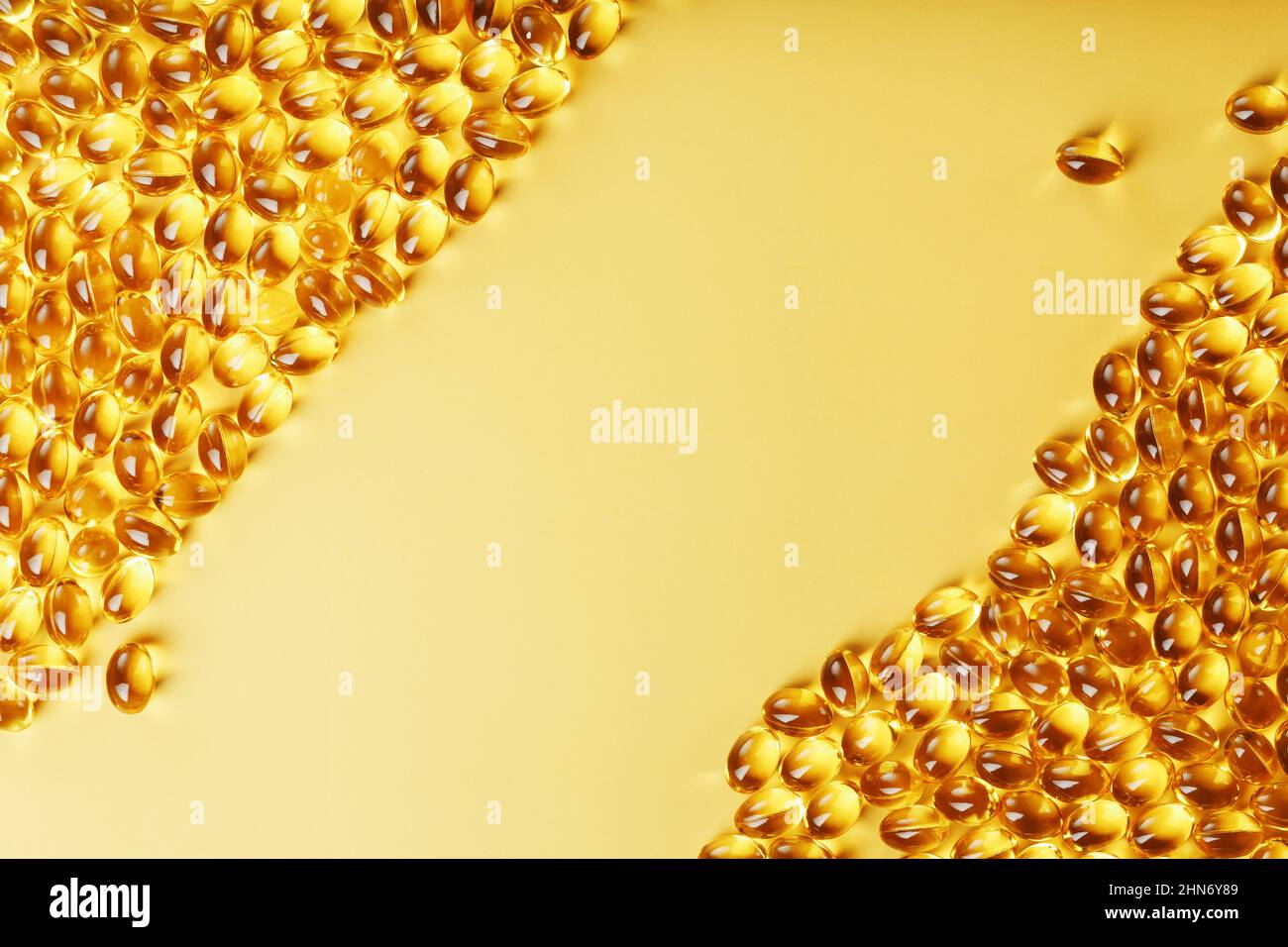 Capsules dans une coquille avec de l'huile de poisson sur fond jaune et un endroit pour le texte. Capsules d'or avec un supplément biologiquement actif pour la santé Banque D'Images