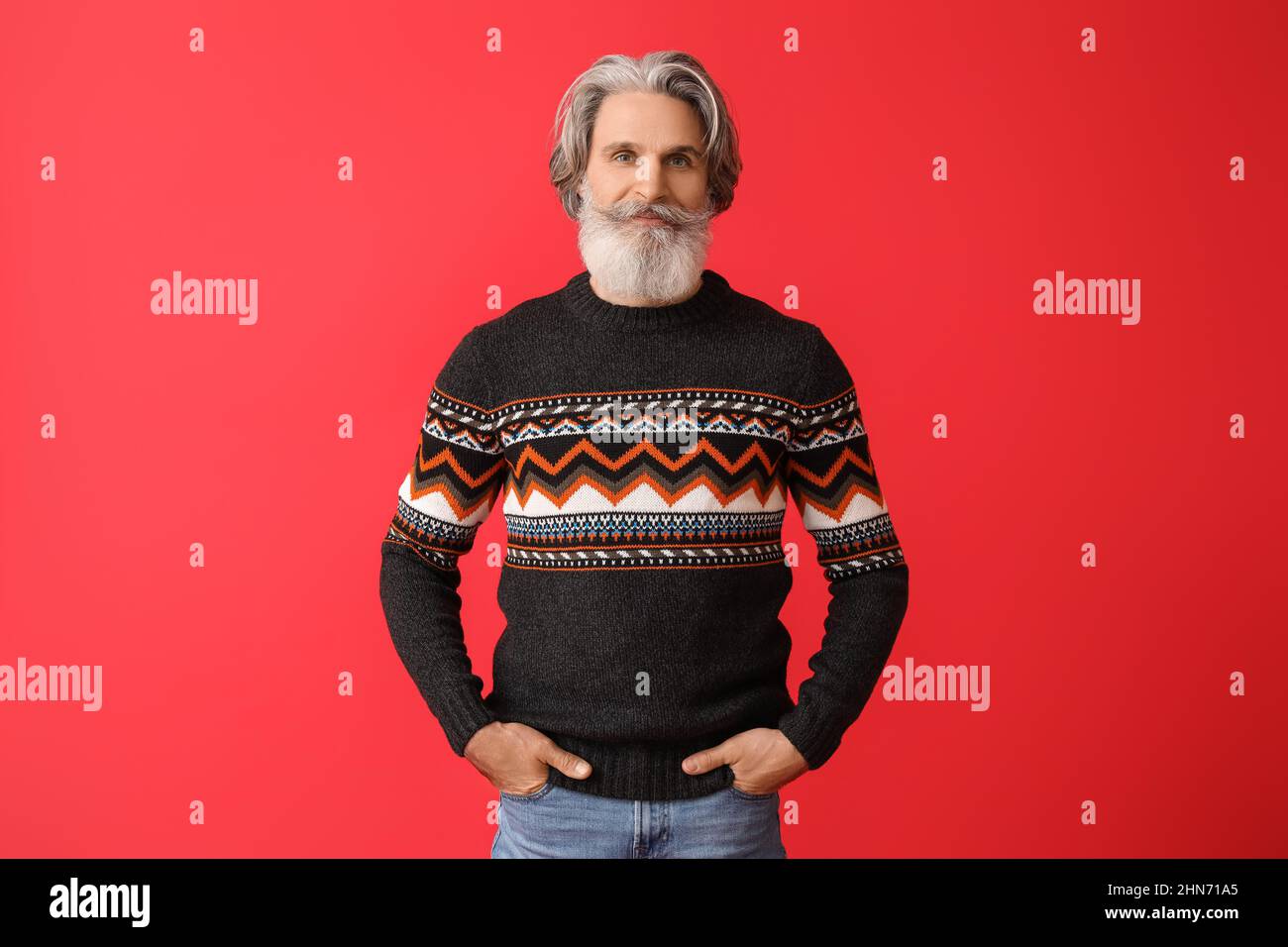 Beau homme âgé en pull tricoté sur fond rouge Photo Stock - Alamy