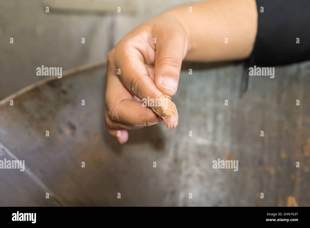 La main de la femme teste la finesse de la mouture du masa, un type de pâte pour les tortillas moulées à partir de maïs traité par les alcalis. Banque D'Images