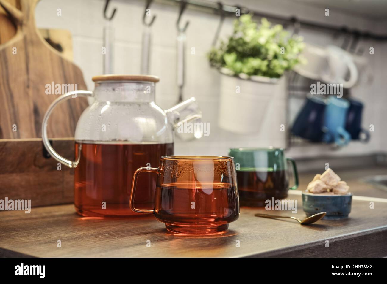 Théière en verre pleine de thé noir avec deux tasses de thé sur le plan de travail de la cuisine Banque D'Images