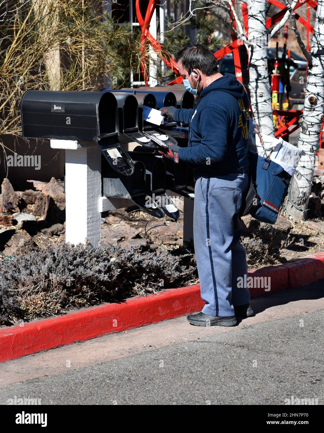 Un mailman américain ou un transporteur de lettres livre le courrier à une rangée de boîtes aux lettres à Santa Fe, Nouveau-Mexique. Banque D'Images