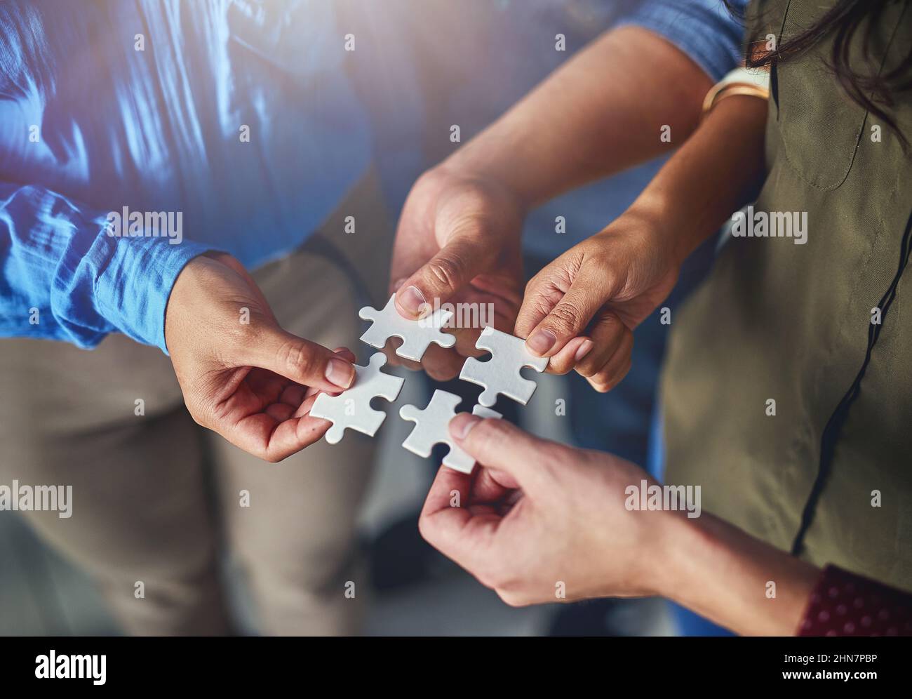 Trouver les bonnes solutions en équipe. Photo d'une équipe d'hommes et de femmes d'affaires mettant des pièces de puzzle ensemble dans un bureau. Banque D'Images