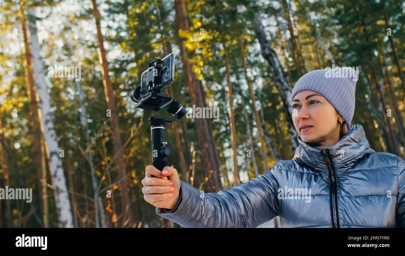 Femme tenant le film portable 3 axes de stabilisation de nacelle en hiver pour smartphone. Fille Blogger faire Selfie, diffusion vidéo Blogging, Vlogging. Opérateur de vidéaste prendre des photos vidéo. Banque D'Images