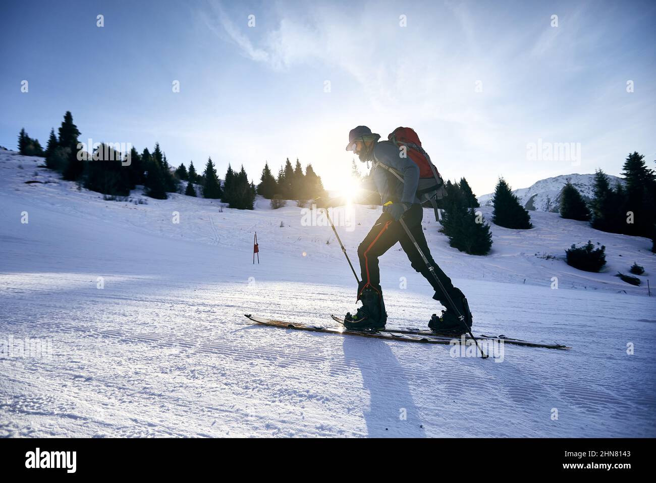 Skieur homme ski en montée avec la barbe et le sac à dos à la station de ski haute neige de Shymbulak. Sport en plein air dans l'arrière-pays en hiver. Banque D'Images