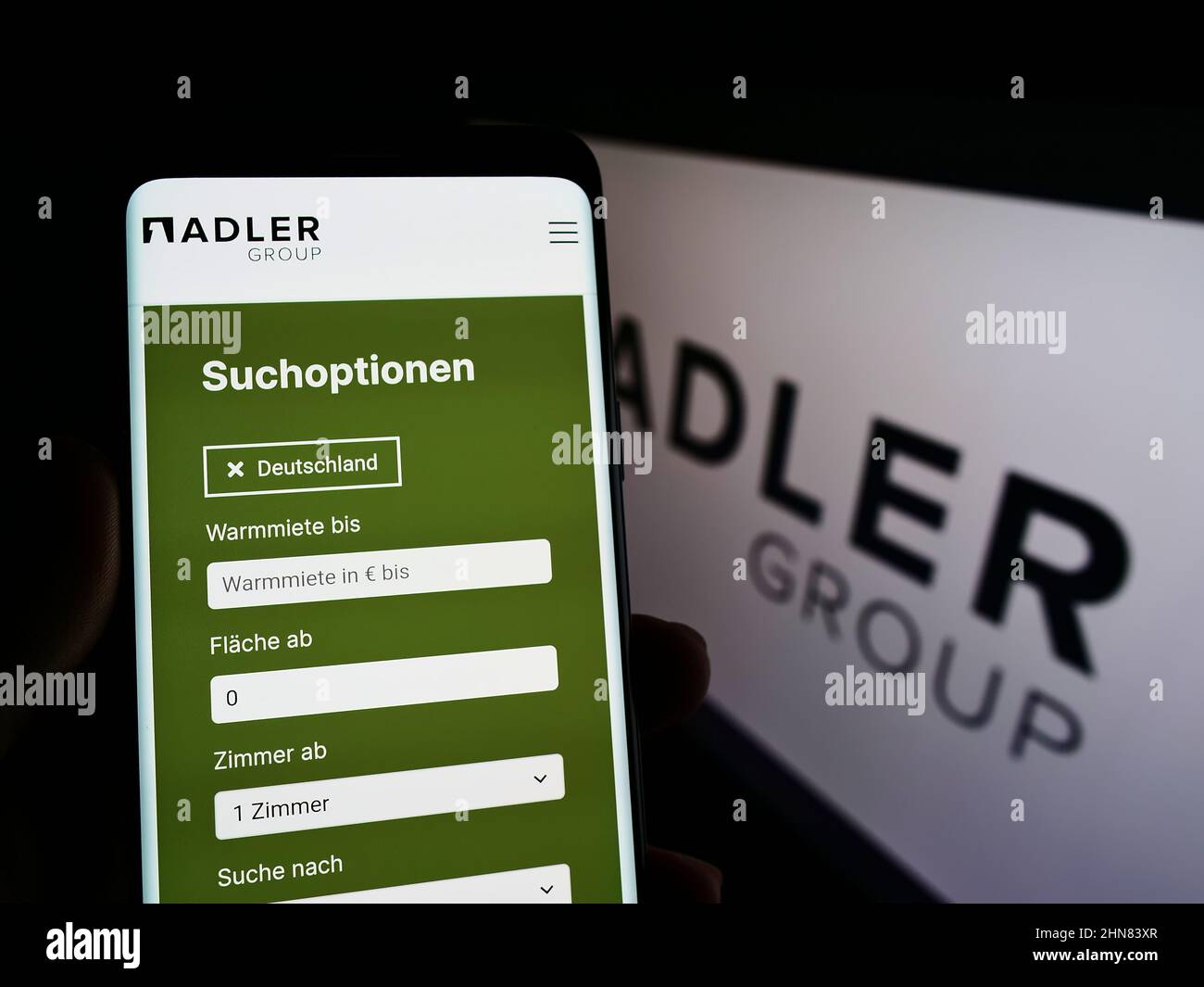 Personne tenant un téléphone portable avec le site de la société immobilière Adler Group S.A. sur écran devant le logo. Concentrez-vous sur le centre de l'écran du téléphone. Banque D'Images
