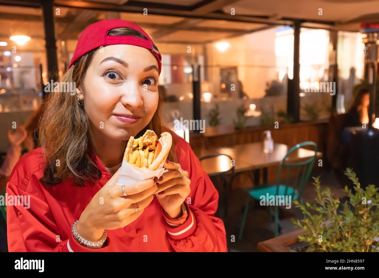 Bonne femme mangeant des gyros ou un hot dog dans un restaurant de restauration rapide Banque D'Images