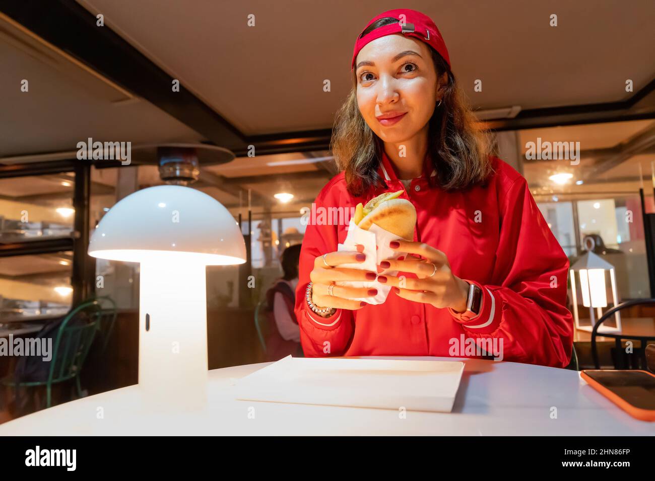 Bonne femme mangeant des gyros ou un hot dog dans un restaurant de restauration rapide Banque D'Images
