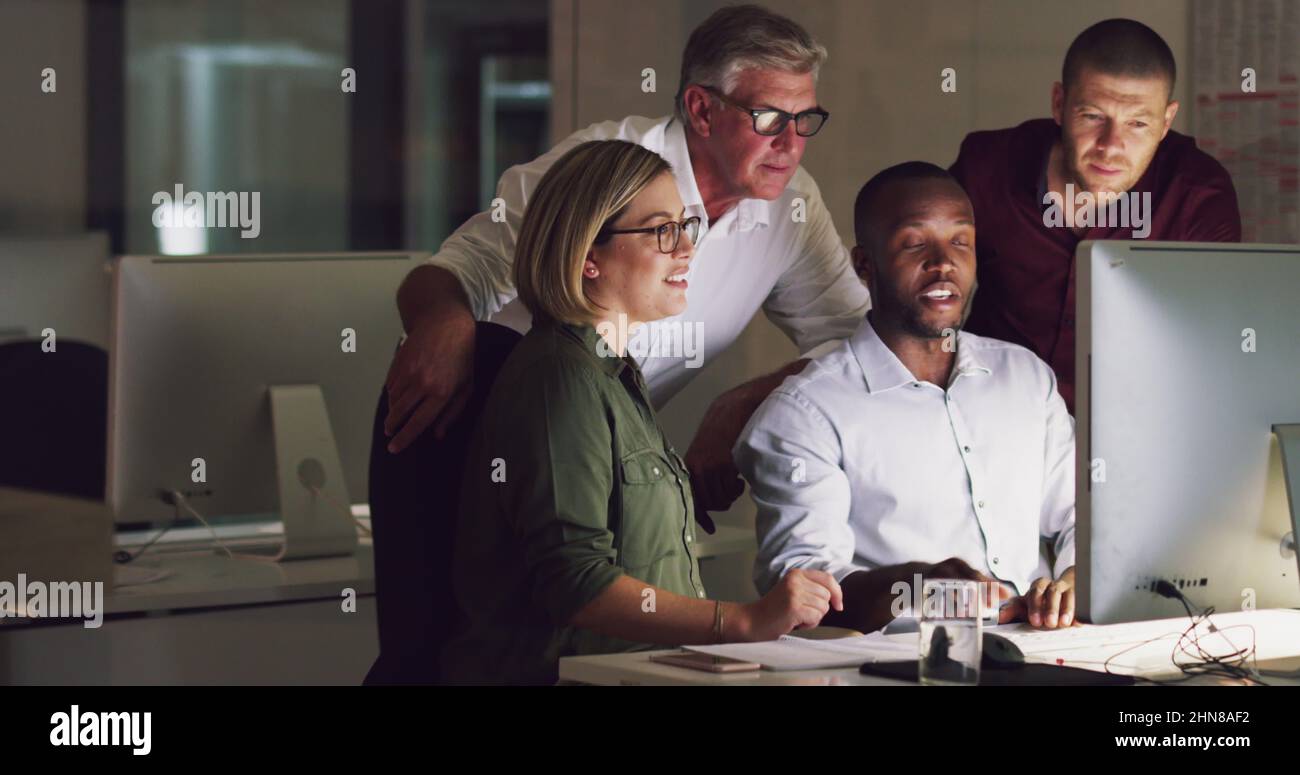 Revoir ensemble leurs grands plans. 4k vidéo d'un groupe d'hommes d'affaires travaillant tard sur un ordinateur dans un bureau. Banque D'Images